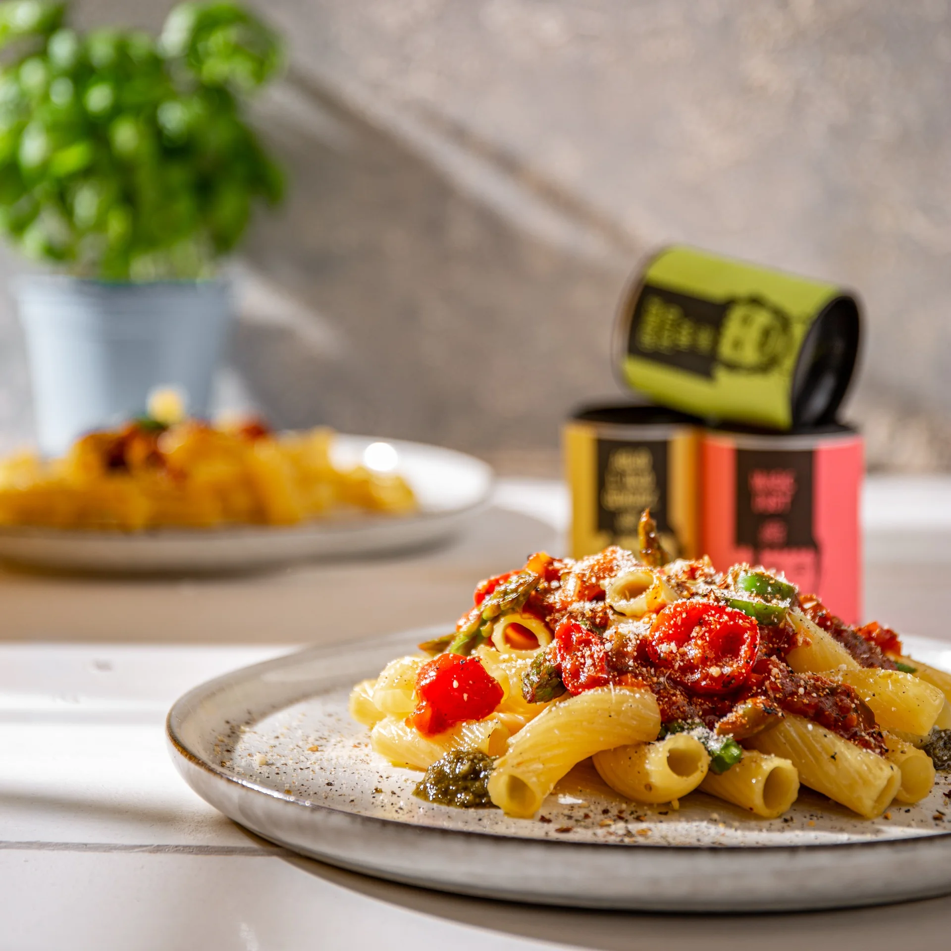 Pastateller mit Tomaten im Vordergrund, dahinter Just-Spices-Gewürzdosen